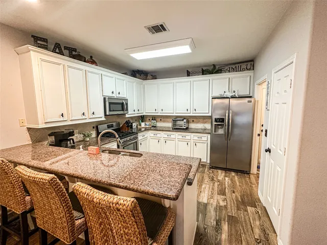 a kitchen with stainless steel appliances granite countertop a refrigerator sink stove microwave and cabinets