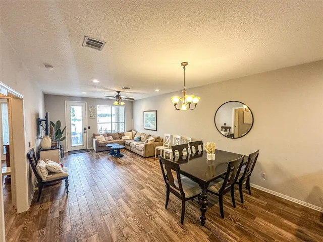 a view of a dining room and livingroom with furniture wooden floor a rug and a chandelier