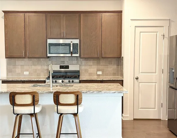 a kitchen with stainless steel appliances granite countertop a sink a stove and a refrigerator