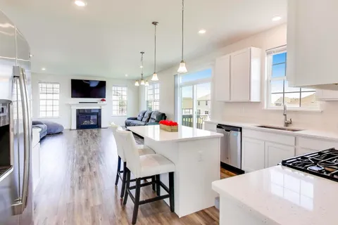 a kitchen with stainless steel appliances a stove a sink a kitchen island a stove a table and chairs