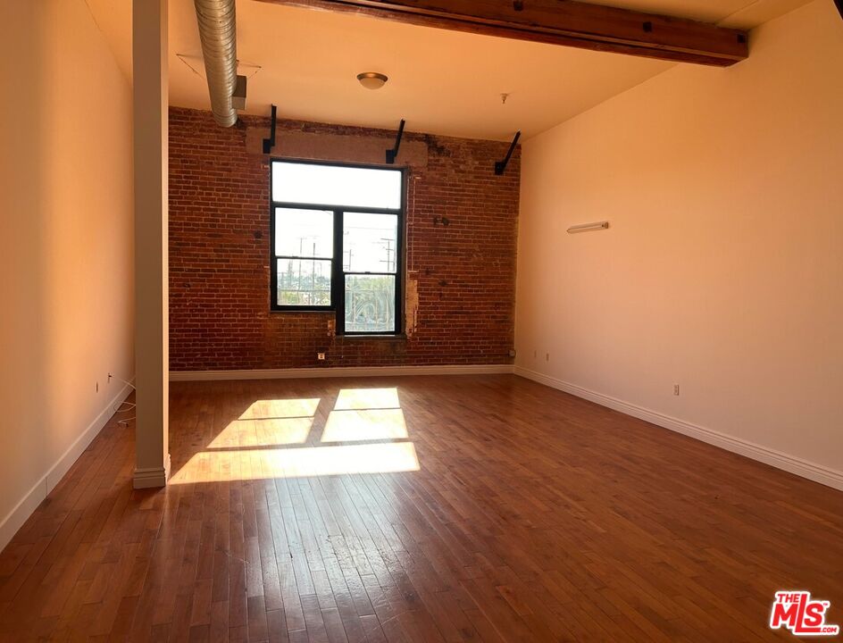 652 Mateo Street, Unit 303 Los Angeles, CA 90021 - Photo 4 of 12 an empty room with wooden floor and windows