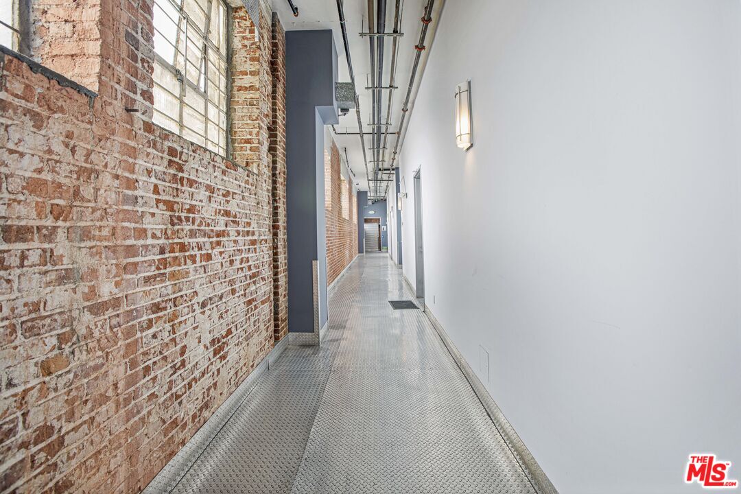 652 Mateo Street, Unit 303 Los Angeles, CA 90021 - Photo 10 of 12 a view of a hallway with wooden floor and brick walls