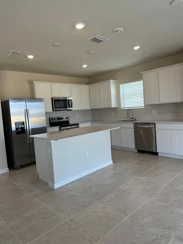 a large kitchen with cabinets a sink and stainless steel appliances