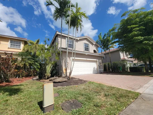 a front view of a house with a yard and potted plants