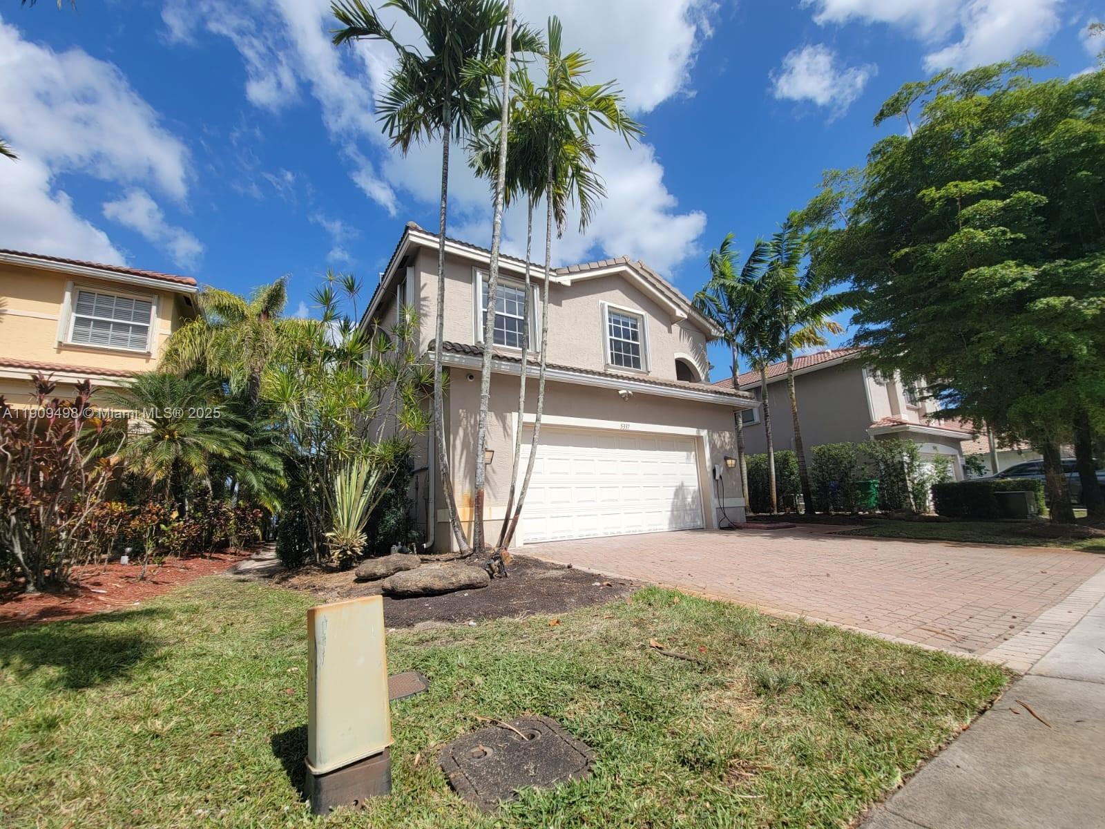 a front view of a house with a yard and potted plants