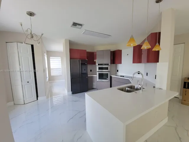 a kitchen with stainless steel appliances granite countertop a sink a stove a refrigerator and a refrigerator