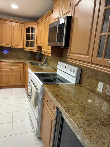 a kitchen with a sink a stove top oven a refrigerator and cabinets