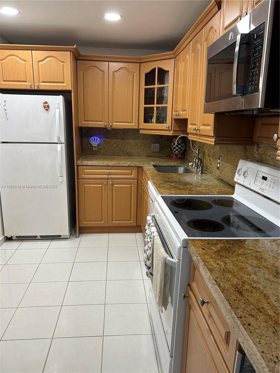 6969 Collins Avenue, Unit 607 Miami Beach, FL 33141 - Photo 10 of 15 a kitchen with a sink a stove top oven a refrigerator and cabinets
