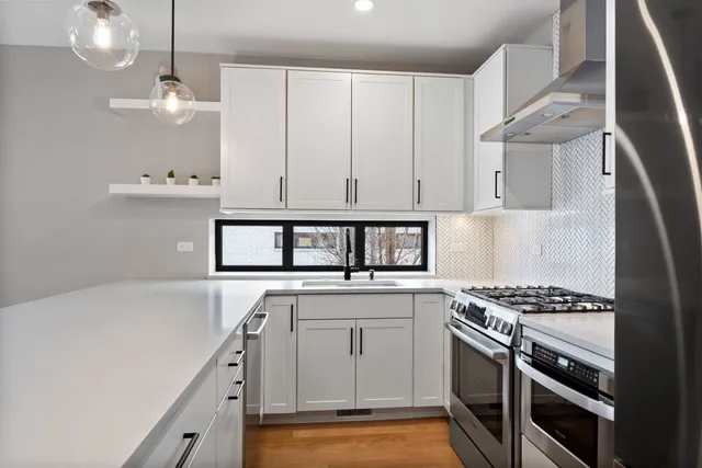 a kitchen with stainless steel appliances a stove a sink and white cabinets