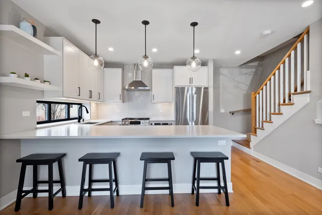 a kitchen with stainless steel appliances kitchen island a table chairs sink and cabinets