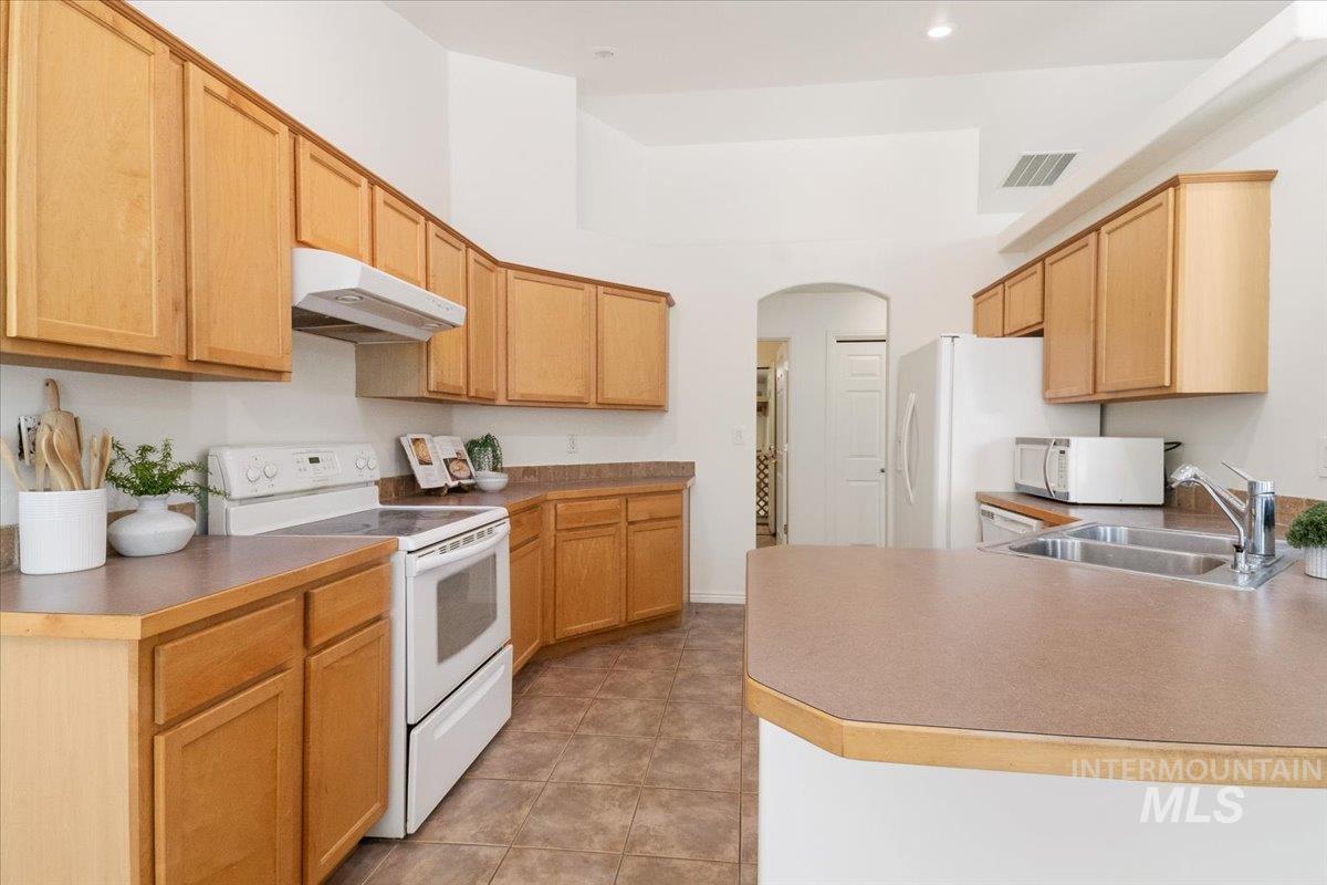 2032 Talus Loop Twin Falls, ID 83301 - Photo 15 of 43 Kitchen featuring light wood cabinetry, white appliances, durable countertops, and tile flooring