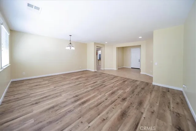 a view of an empty room with window and wooden floor