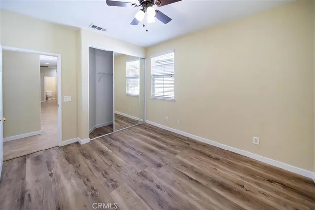a view of a hallway with wooden floor and a bathroom