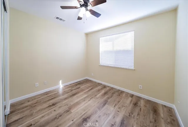 an empty room with closet and a ceiling fan