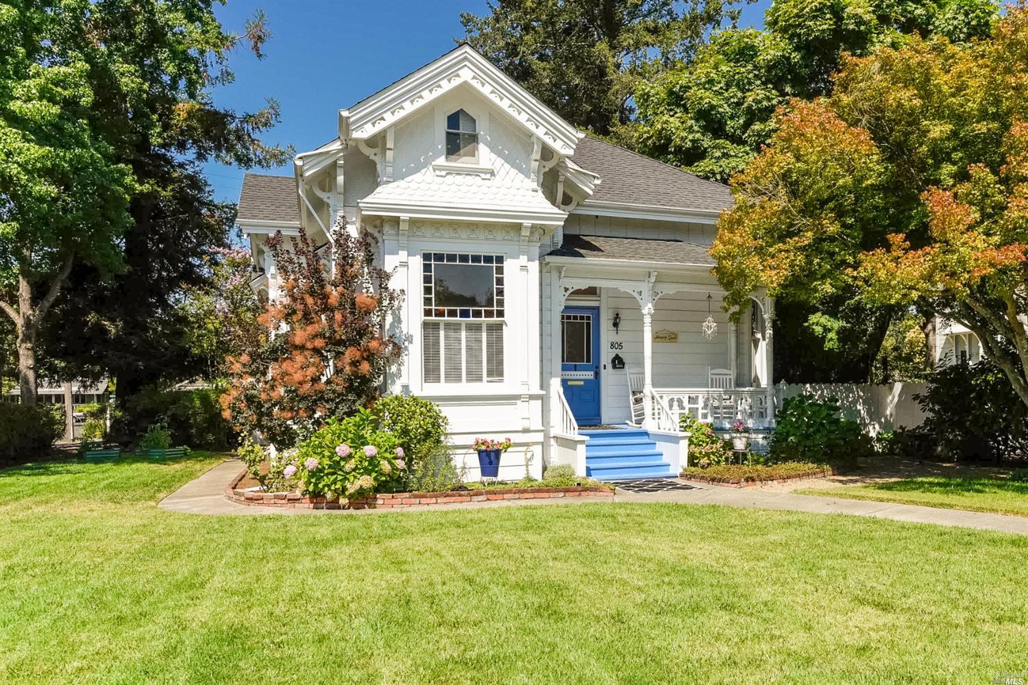 a front view of a house with garden and trees