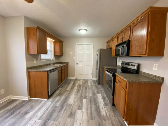 a kitchen with stainless steel appliances granite countertop a stove a sink dishwasher and a refrigerator with wooden floor