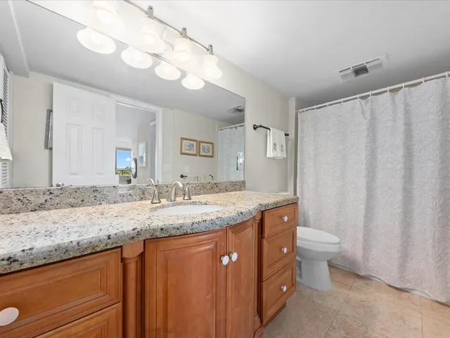 a bathroom with a granite countertop sink a toilet and a mirror