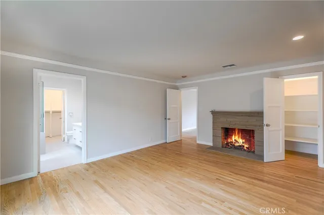 a view of an empty room with wooden floor fireplace and a window