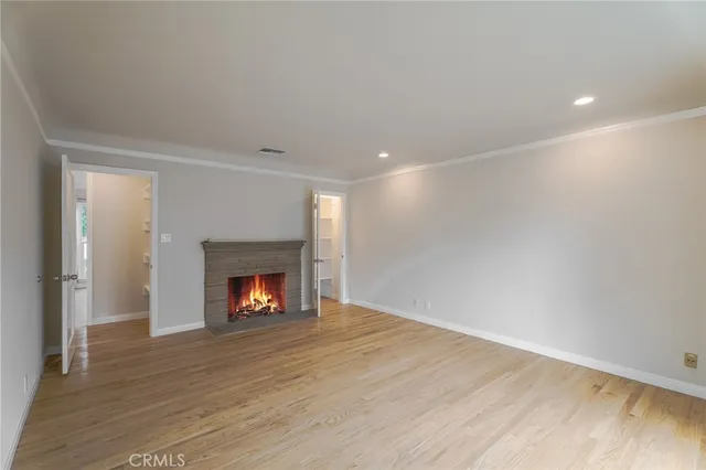 a view of an empty room with wooden floor fireplace and a window