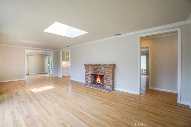an empty room with wooden floor fireplace and windows