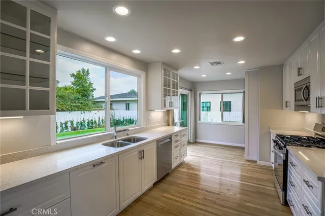 a large kitchen with stainless steel appliances a large counter top a stove and a wooden floors