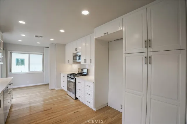 a open kitchen with white cabinets and stainless steel appliances