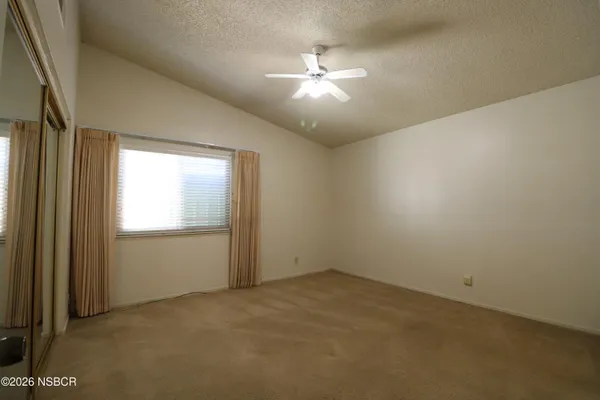 an empty room with chandelier fan and windows