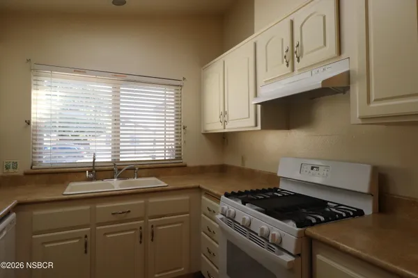 a kitchen with granite countertop a sink a stove and cabinets