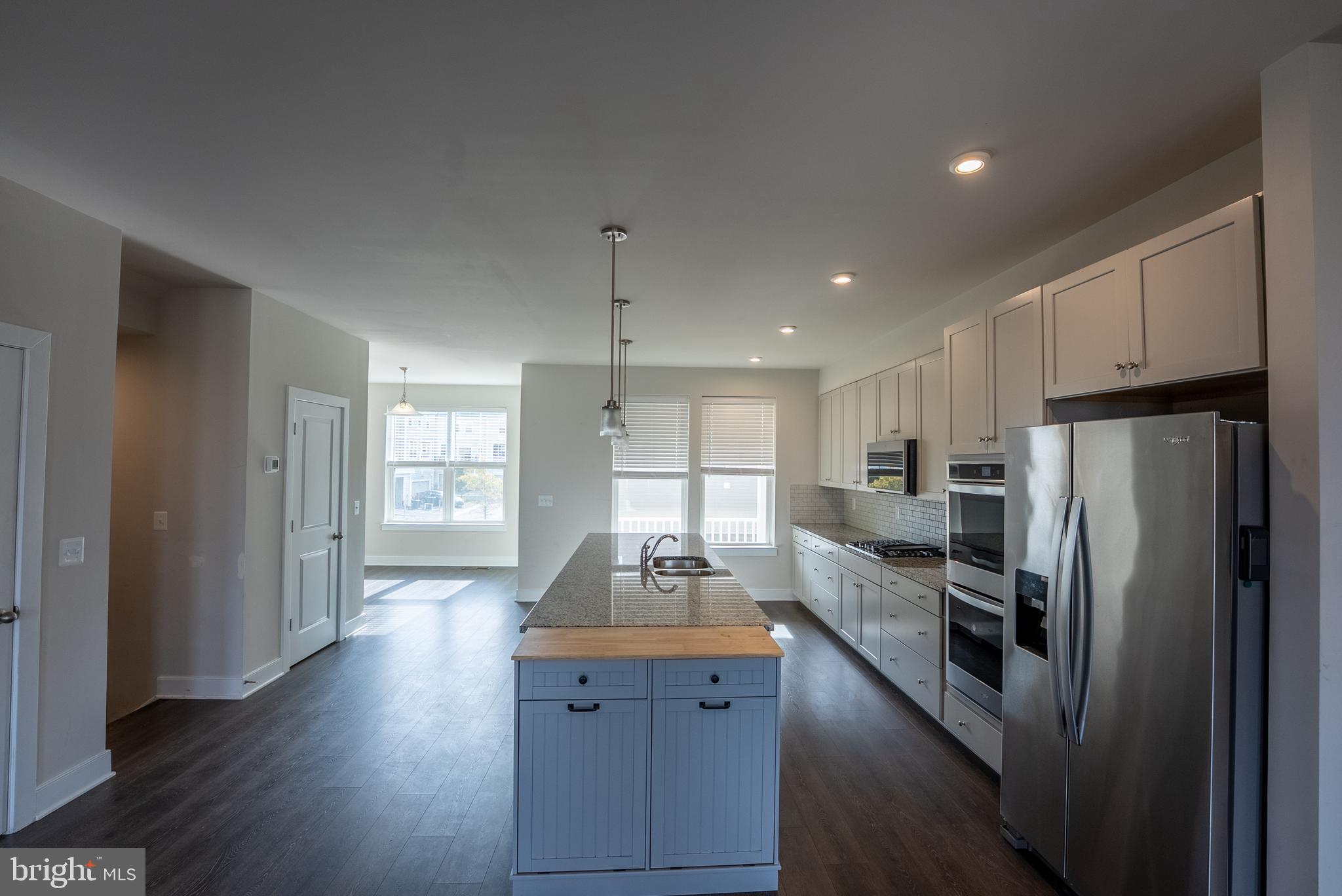 1622 Sandpiper Bay Loop Dumfries, VA 22026 - Photo 27 of 47 a kitchen with kitchen island wooden floors white cabinets and stainless steel appliances