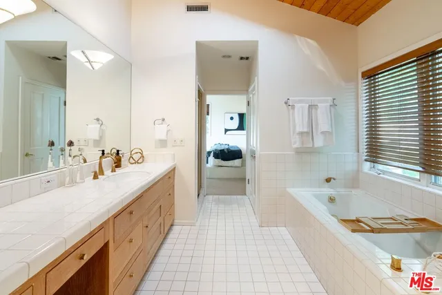a spacious bathroom with a tub a double vanity sink and a large mirror