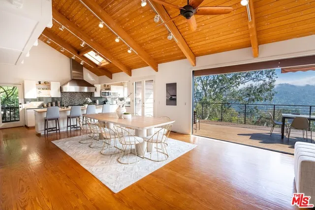 a dining room with wooden floor and large windows