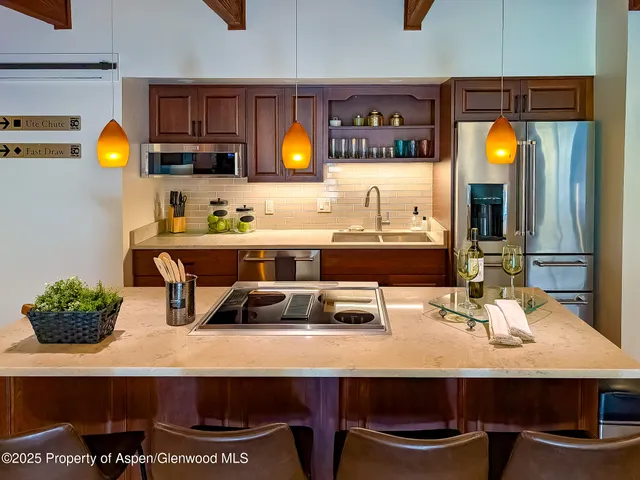 a room with stainless steel appliances a sink table and chairs