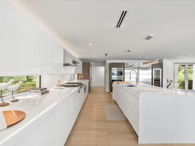 a large white kitchen with granite countertop a large counter top and stainless steel appliances