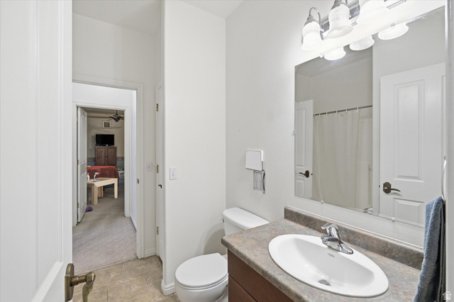 560 East 700 North Logan, UT 84321 - Photo 14 of 32 Bathroom featuring a single vanity with an oval sink, a stone-look countertop, and a wood-finish cabinet