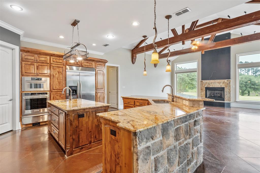 20389 County Road 178 Flint, TX 75762 - Photo 10 of 40 Kitchen featuring two islands with granite countertops, stainless steel appliances, wood cabinetry, and a stone-clad island base
