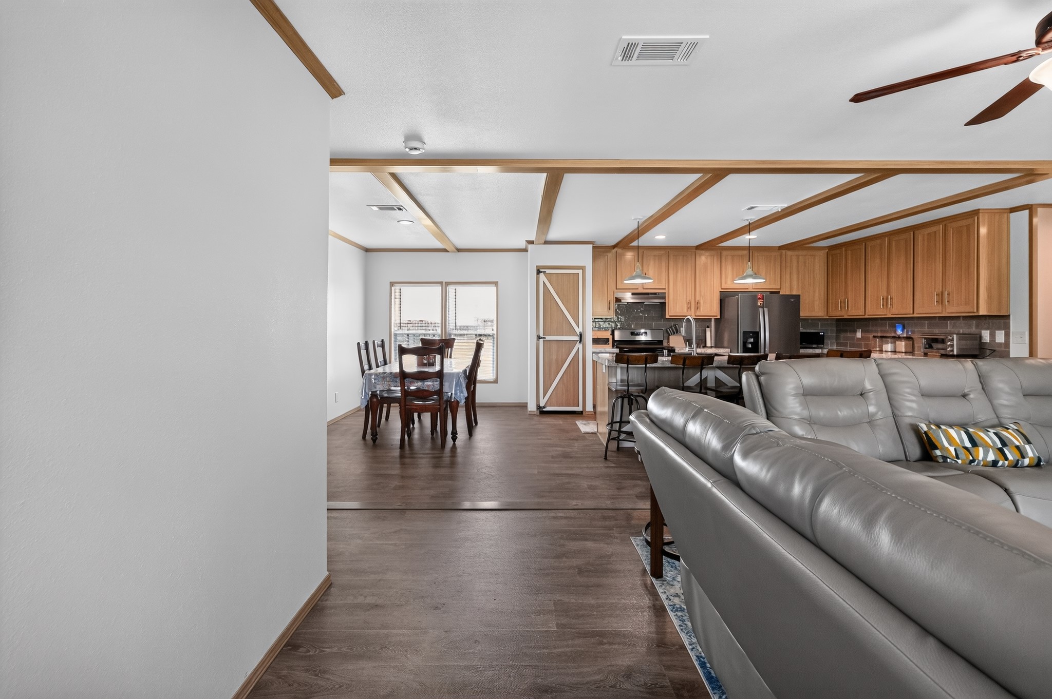 1134 Switchgrass Road Salado, TX 76571 - Photo 11 of 28 An inviting open-concept layout connects the kitchen, dining, and living areas with warm wood flooring and exposed beam ceilings.