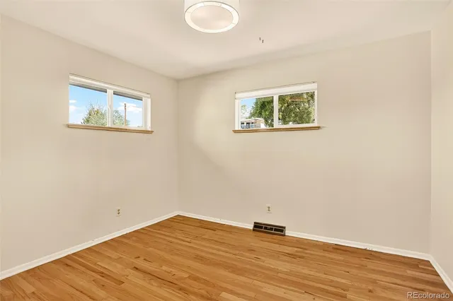 an empty room with wooden floor and window