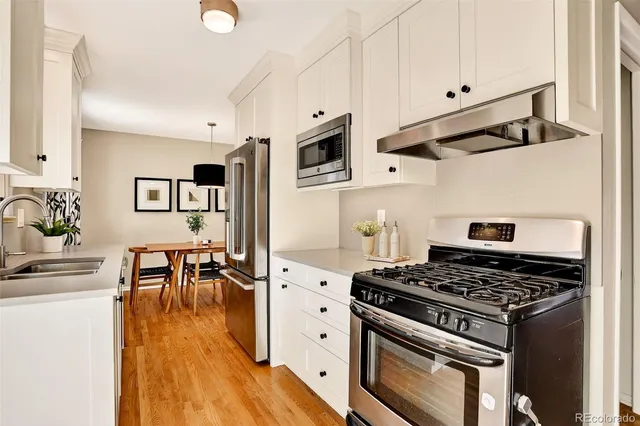 a kitchen with stainless steel appliances a stove a sink dishwasher and cabinets with wooden floor