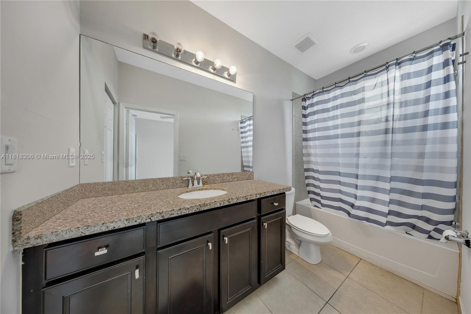 14776 Southwest 10th Street, Unit 10501 Pembroke Pines, FL 33027 - Photo 7 of 16 a bathroom with a granite countertop sink a toilet a mirror and shower curtain
