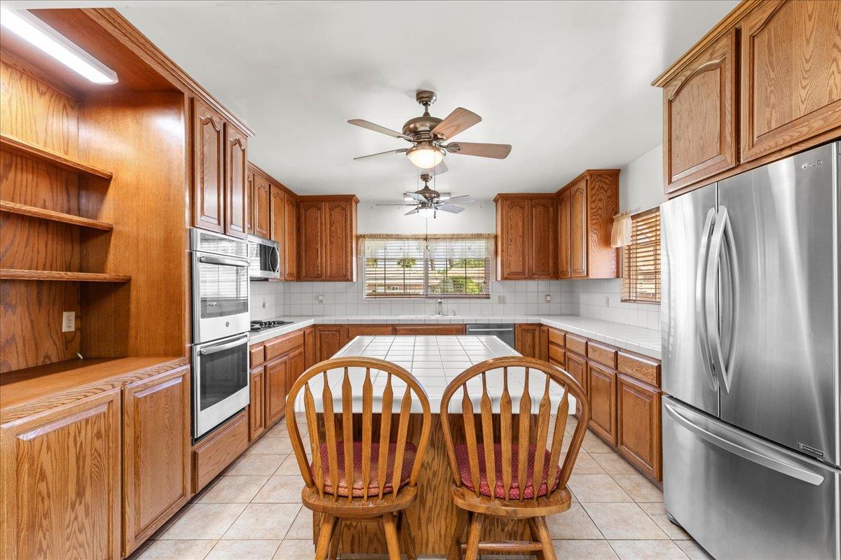 4701 Lone Tree Road Valley Home, CA 95361 - Photo 21 of 59 a kitchen with stainless steel appliances granite countertop a refrigerator a stove a sink dishwasher with a dining table and chairs