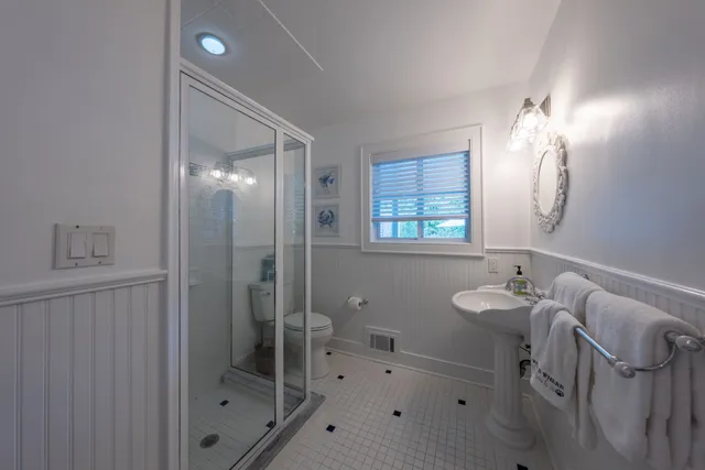 a bathroom with a bathtub shower sink mirror and toilet