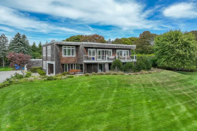 a view of a house with a big yard plants and large trees
