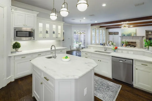 a kitchen that has a sink a microwave oven a stove and white cabinets with wooden floor