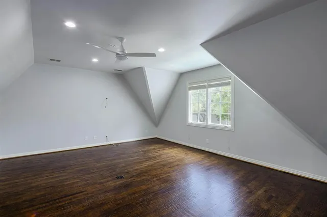 an empty room with wooden floor ceiling fan and windows