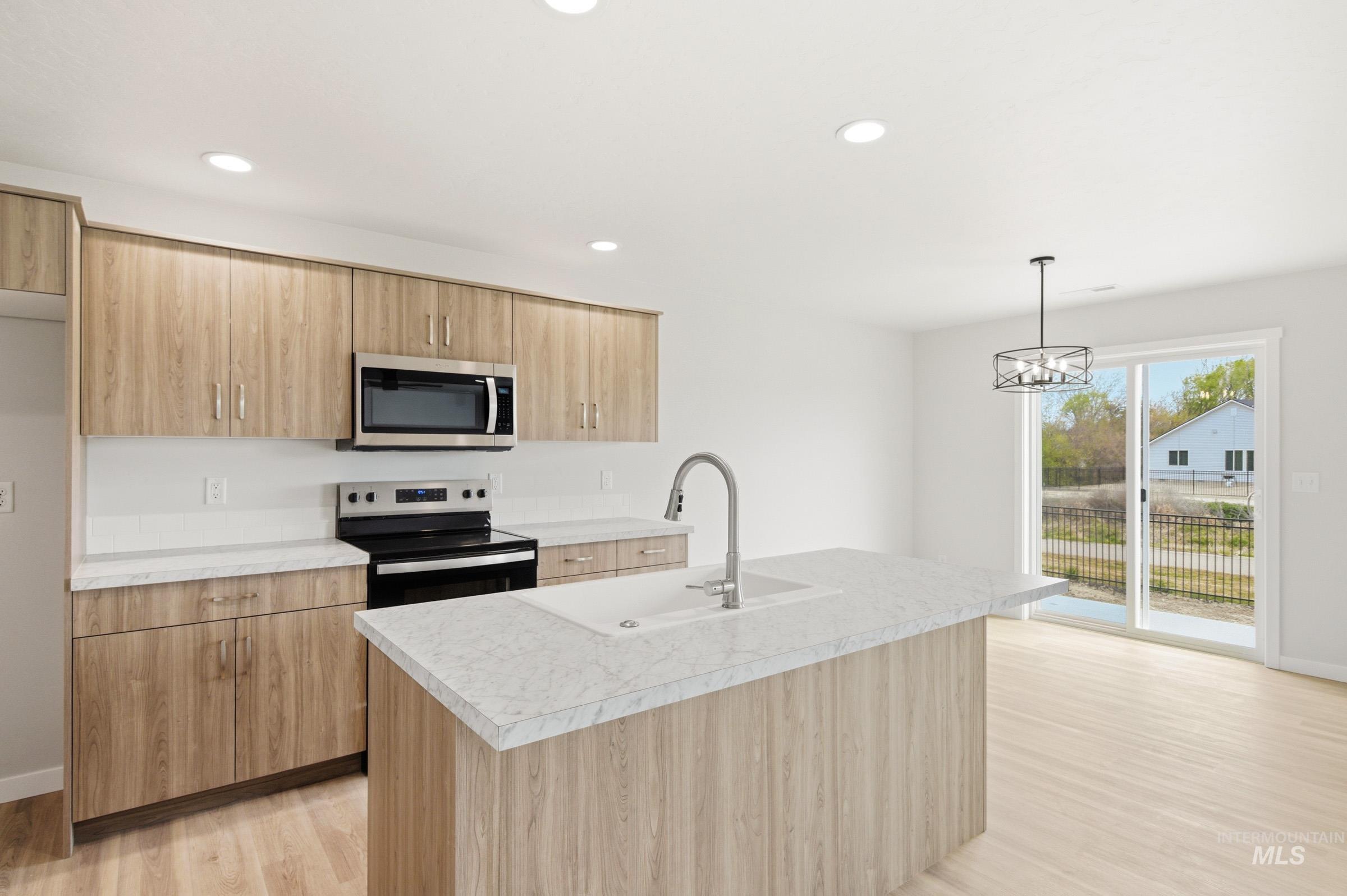 2446 West Fallon Loop Nampa, ID 83651 - Photo 10 of 19 Kitchen featuring stainless steel appliances, light countertops, light wood finished floors, an island with sink, and modern cabinets