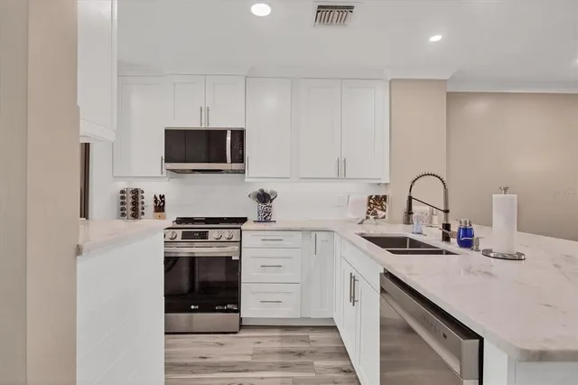 a kitchen with white cabinets stainless steel appliances and a sink