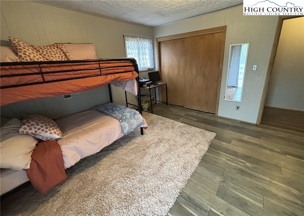 224 Alex Wellborn Road Deep Gap, NC 28618 - Photo 20 of 26 a bedroom with a bed and wooden floor