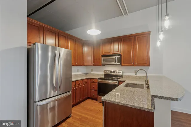 a kitchen with granite countertop stainless steel appliances cabinets a sink and a refrigerator