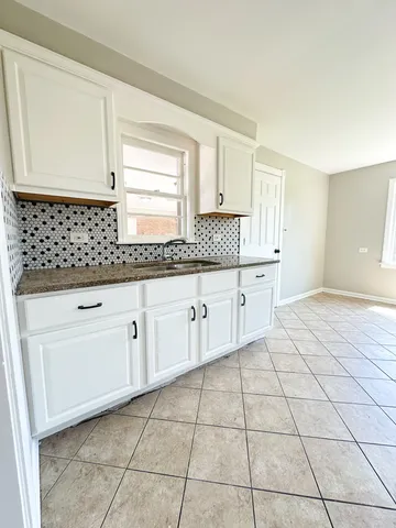 a kitchen with granite countertop white cabinets and sink