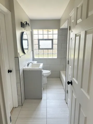 a bathroom with a granite countertop sink toilet a mirror and tub